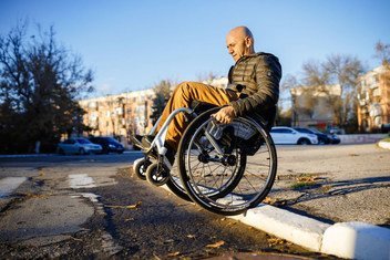 It takes Dmitry Kuzuk, an activist for persons with disabilities, a lot of skill and effort to navigate through city streets in his wheelchair.