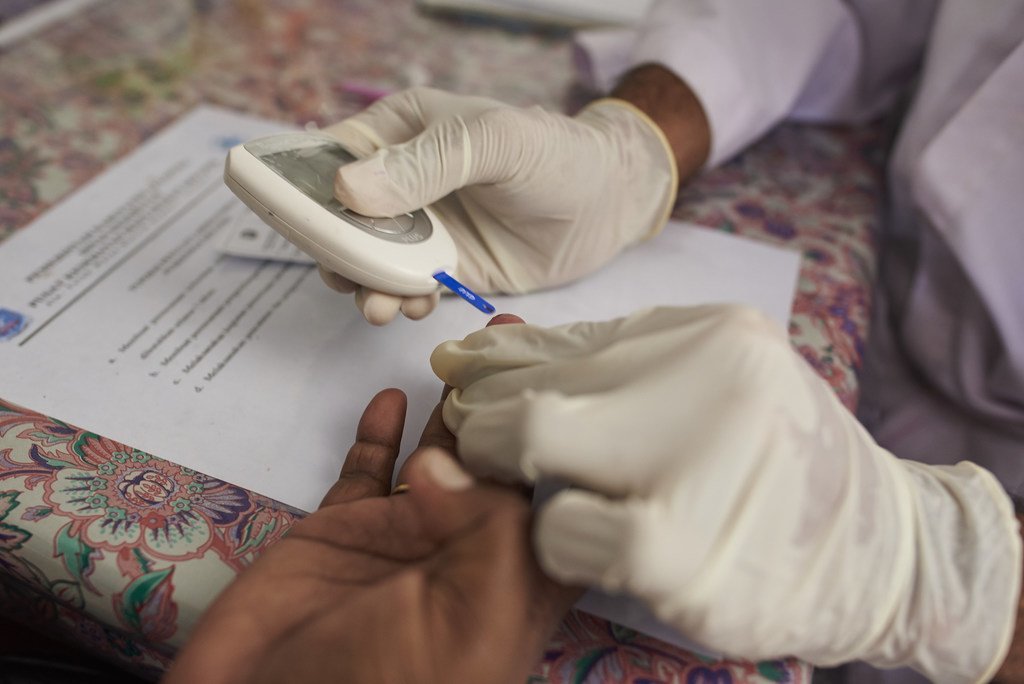 一名卫生工作者在印度尼西亚的一个社区卫生中心检查妇女的血糖水平。