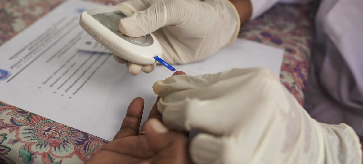 इण्डोनेशिया के जयापुर में एक स्वास्थ्यकर्मी महिला के रक्त में शर्करा की जाँच करते हुए. 