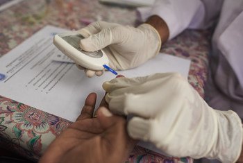 أحد العاملين الصحيين يفحص مستوى السكر في الدم لمريضة في أحد مراكز الصحة المجتمعية في مقاطعة جيابورا في إندونيسيا.