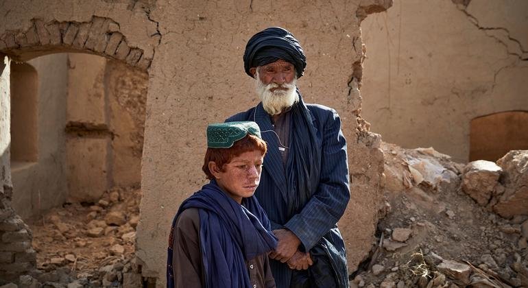 سيد محمد وابنه يقفان أمام منزلهما المتضرر في مارجا، أفغانستان.