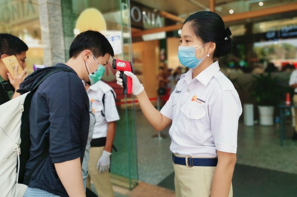在缅甸仰光一个购物中心入口处，工作人员在检查顾客的体温。