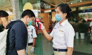 Trabajadores toman la temperatura de los clientes para descartar el coronavirus en un centro comercial de Yangon, Myanmar.