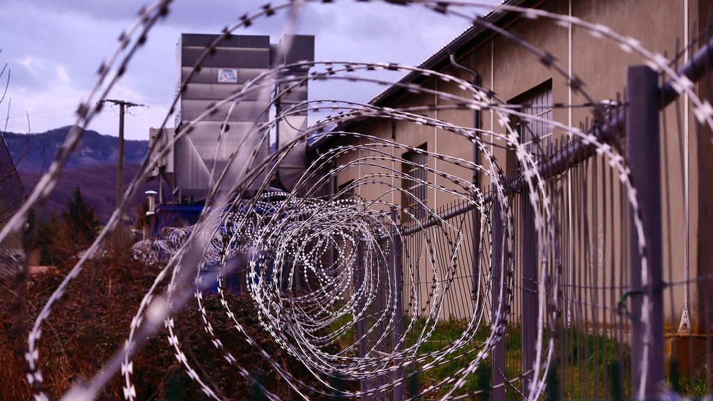 Une clôture en fil de fer barbelé entoure un centre de détention.