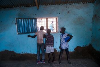 Children look out of a window in South Sudan.