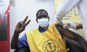 A health care worker in Sudan flashes a V for victory sign as he is vaccinated against COVID-19.