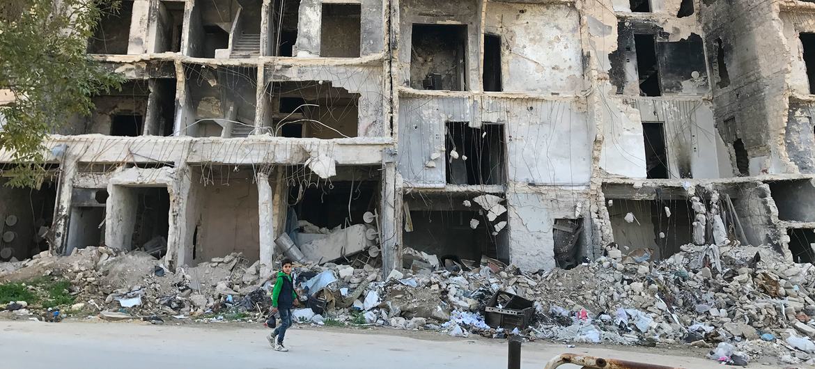 Menino passa por apartamentos destruídos em Alepo, Síra. 