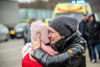 यूक्रेन से सीमा पार करके पोलैण्ड पहुँचने के बाद, एक महिला अपनी बच्ची के साथ.