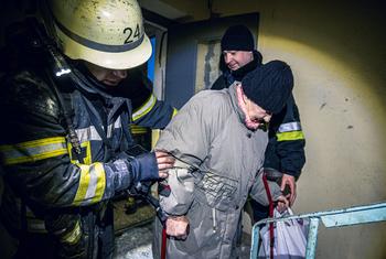 На фото: пожарные эвакуируют жильцов многоквартирного дома, пострадавшего от авиаудара.