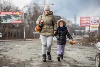 यूक्रेन के कीयेफ़ के नज़दीक बूचा में एक माँ अपनी बेटी के साथ हिंसा से बचकर निकल रही है.