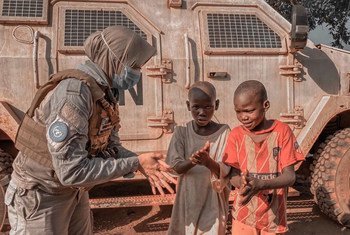A peacekeeper with MINUSCA, the UN mission in the Central African Republic, explains to two young boys how to properly apply hand sanitizer as protection against coronavirus.