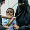 السيدة اليمنية آسيا السيد علي، العاملة في مجال الصحة، تفحص طفلا صغيرا يعاني من سوء التغذية الحاد.