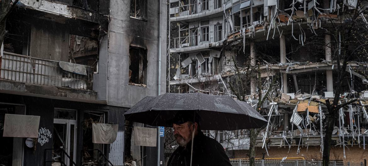 A man walks past destroyed apartment buildings in Kharkiv, Ukraine