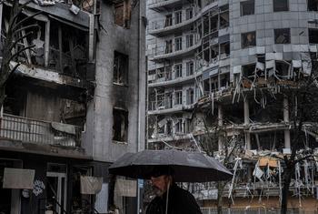 A man walks past destroyed apartment buildings in Kharkiv, Ukraine