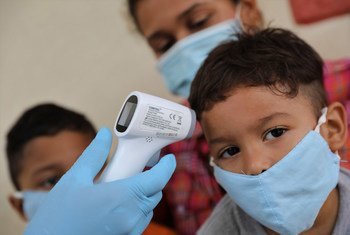 Un médico toma la temperatura a una familia de retornados en un refugio temporal en Venezuela. Kariani Rivero de Maroto, de 27 años y sus hijos, Diego y Matías, de 7 y 3 años, regresaron de Colombia después de que ella perdiera su trabajo en una peluquerí