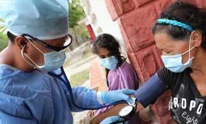 El Dr. Douglas Martínez toma la presión arterial de un migrante venezolano que regresa a la cuarentena en un refugio temporal durante Covid-19.