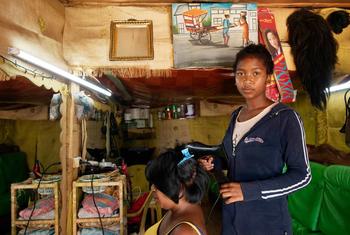 Une jeune femme travaille dans un salon de coiffure à Madagascar.