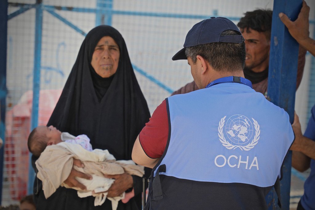 联合国人道协调厅的工作人员协助一名妇女将她四天大的孙子带到叙利亚霍尔营地的一家诊所。 （2019年6月16日）