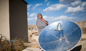 A woman in Afghanistan stands next to a solar cooking disc. (31 May 2015)