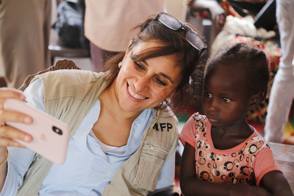 عبير عطيفة، المتحدثة الإعلامية باسم برنامج الأغذية العالمي تلتقط صورة تذكارية مع طفلة، خلال زيارة ميدانية إلى منطقة النيل الأزرق في السودان.