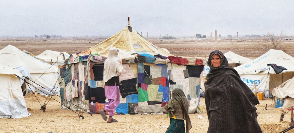 A woman walks in front of tents at an internally displaced persons (IDP) site in Kandahar, southern Afghanistan.