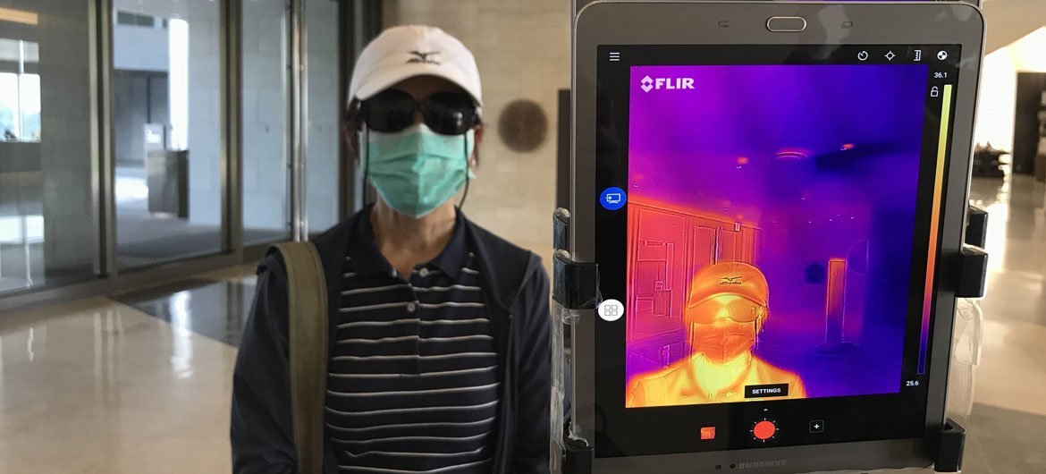 An infrared thermometer is used to check the temperature of guests at a hotel entrance in Yangon, Myanmar.