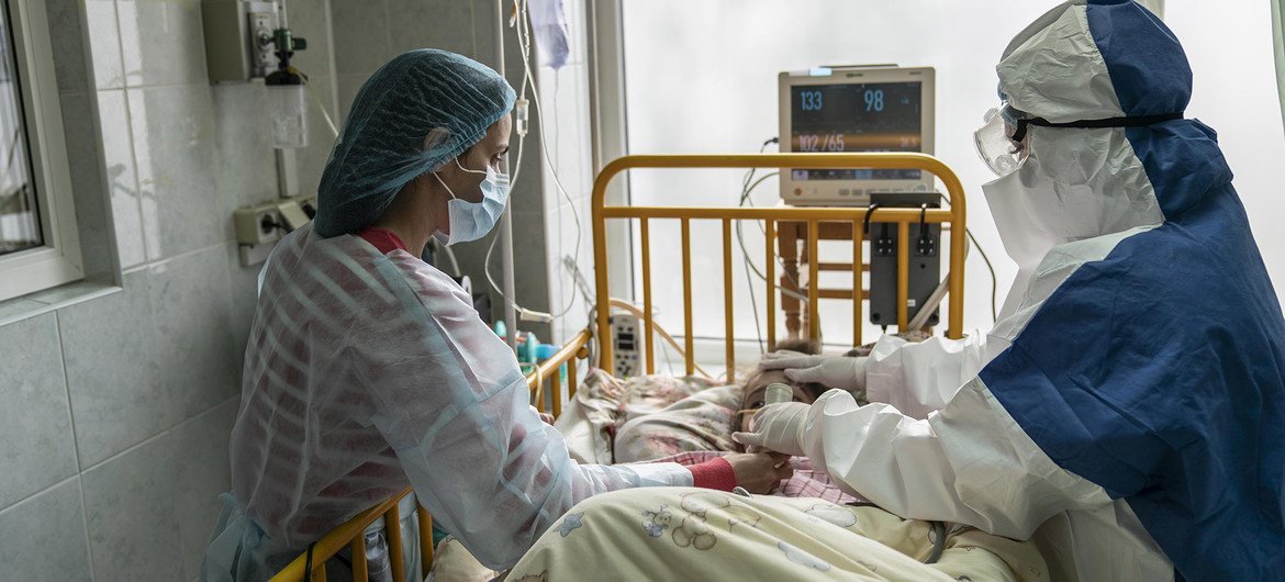 乌克兰一重症监护病房里一名患有新冠病毒病的女孩接受其母亲和医生的照顾。