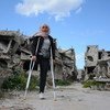 نور (16 عاما) تقف في حي كرم الزيتون في حمص بسوريا، وقد دمرته الحرب وهجره بعض سكانه.