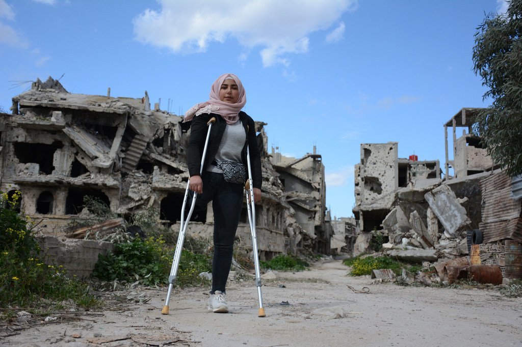 نور (16 عاما) تقف في حي كرم الزيتون في حمص بسوريا، وقد دمرته الحرب وهجره بعض سكانه.
