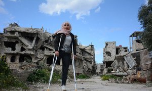 Nour, 16, stands in her war-ravaged and now partially inhabited neighbourhood of Karm Al-zaitoun in Homs city, Syria. 