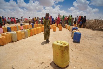 A child stands next to empty containers lined up by people to collect water from a tanker at an IDP camp in Sool region, Somalia.