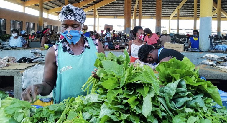 بائعون في أحد الأسواق في أنغولا يتبنون تدابير لوقاية أنفسهم من المرض خلال جائحة كوفيد-19.