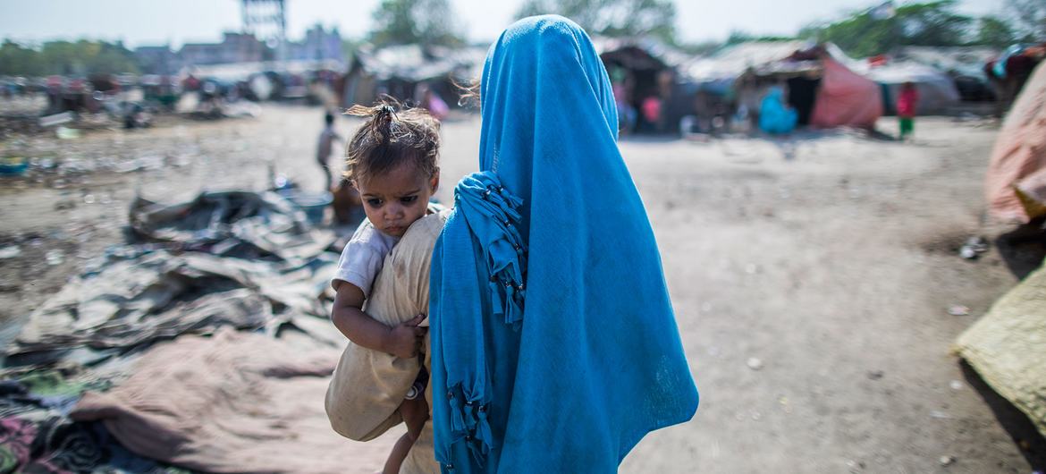 印度的一个贫民窟里，一位母亲抱着她的孩子。