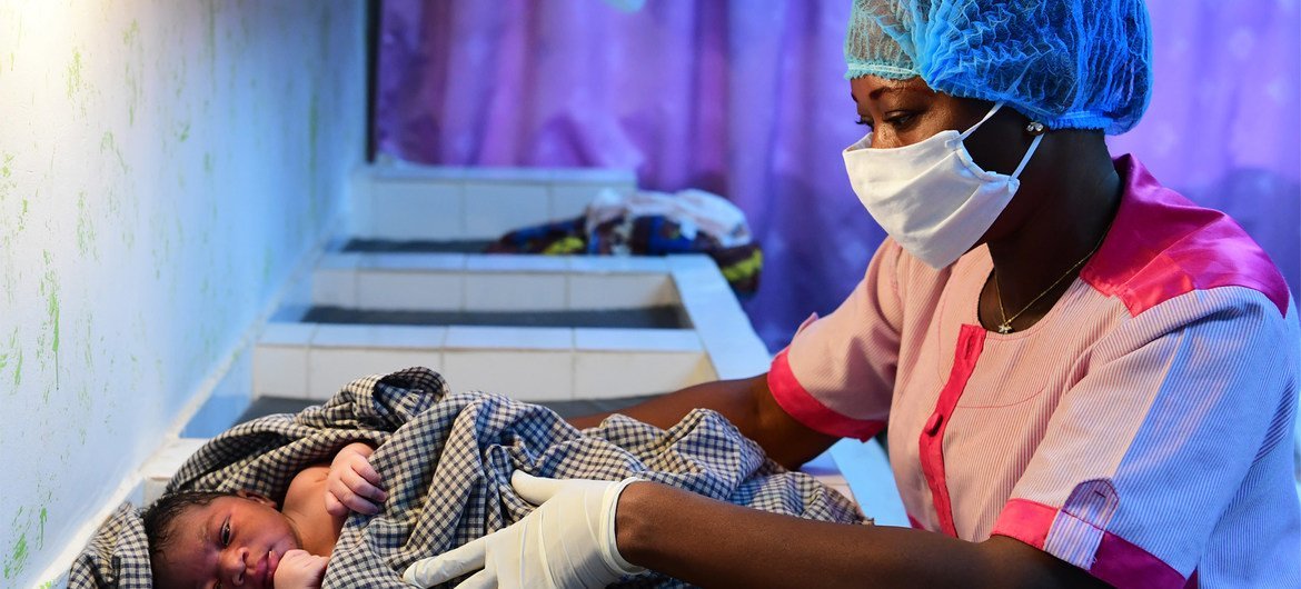 科特迪瓦南部城市阿比让市郊，一家医院的护士戴着口罩和手套照顾新生儿。