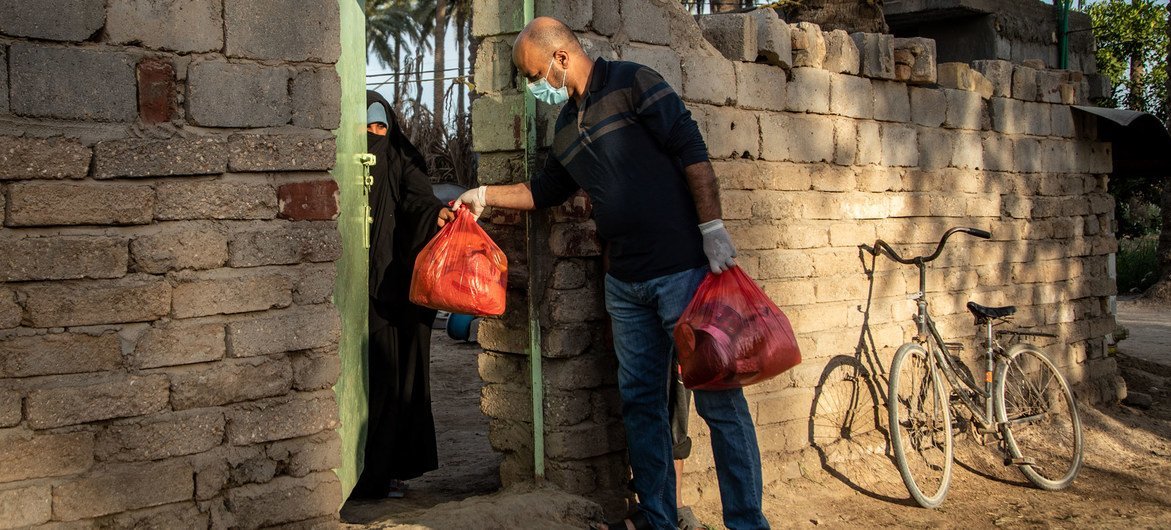No Iraque, um voluntário que trabalha para um grupo apoiado pelo Pnud entrega uma sacola de alimentos a uma família vulnerável no distrito de Tawrij, localizada nos arredores de Karbala, Iraque.