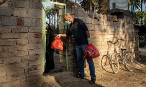 No Iraque, um voluntário que trabalha para um grupo apoiado pelo Pnud entrega uma sacola de alimentos a uma família vulnerável no distrito de Tawrij, localizada nos arredores de Karbala, Iraque.