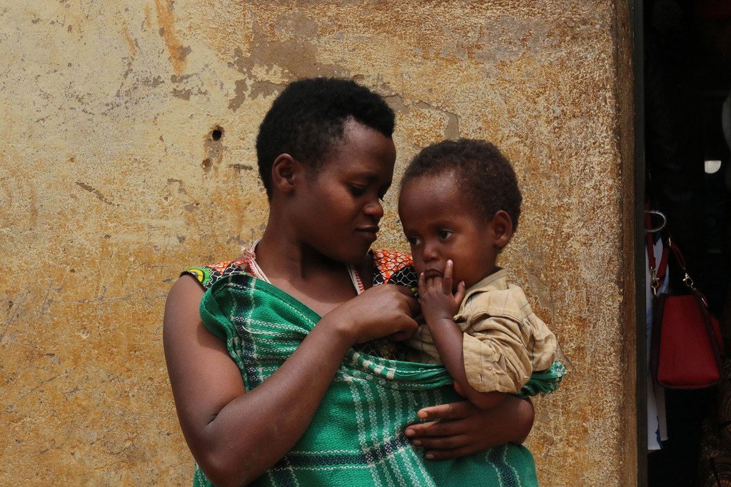 Une mère tient son enfant devant sa maison dans le camp de réfugiés de Kiziba au Rwanda.