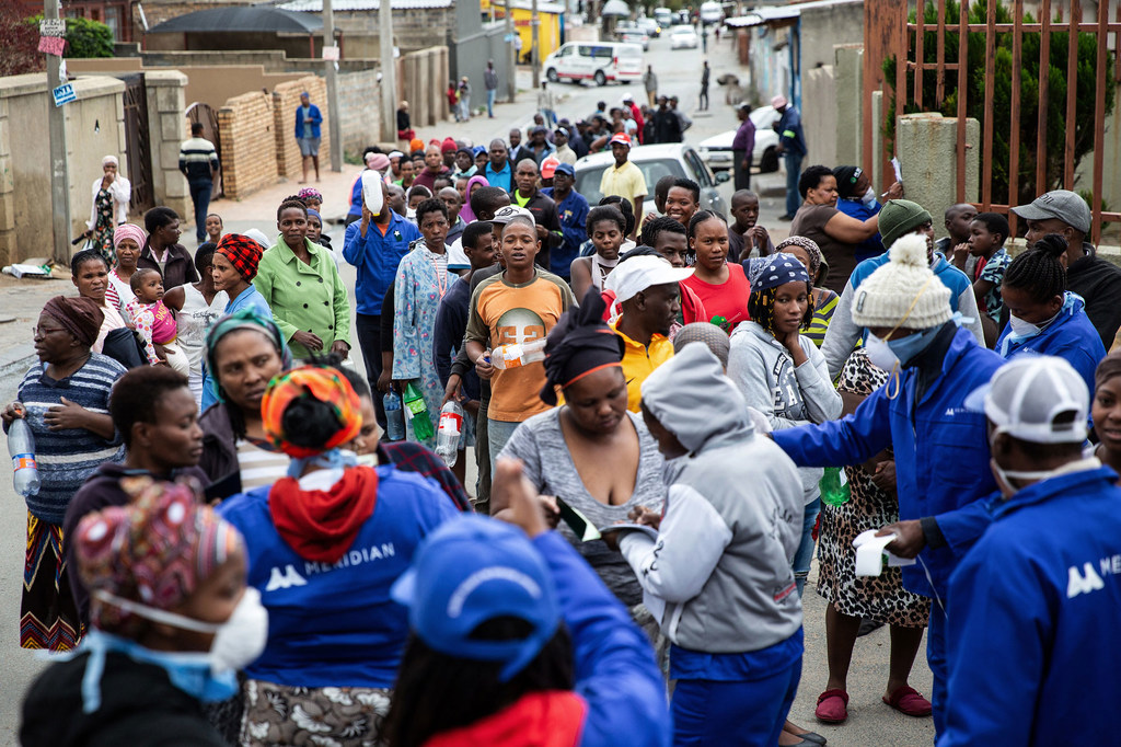 La gente hace cola para rellenar sus recipientes de desinfectante de manos durante el confinamiento por COVID-19 en Alexandra Township, Johannesburgo, en Sudáfrica (foto de archivo).