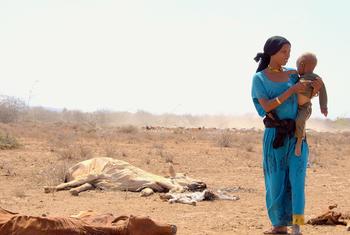 Une mère avec son enfant devant une carcasse d'animal mort en raison de la sécheresse au Kenya.