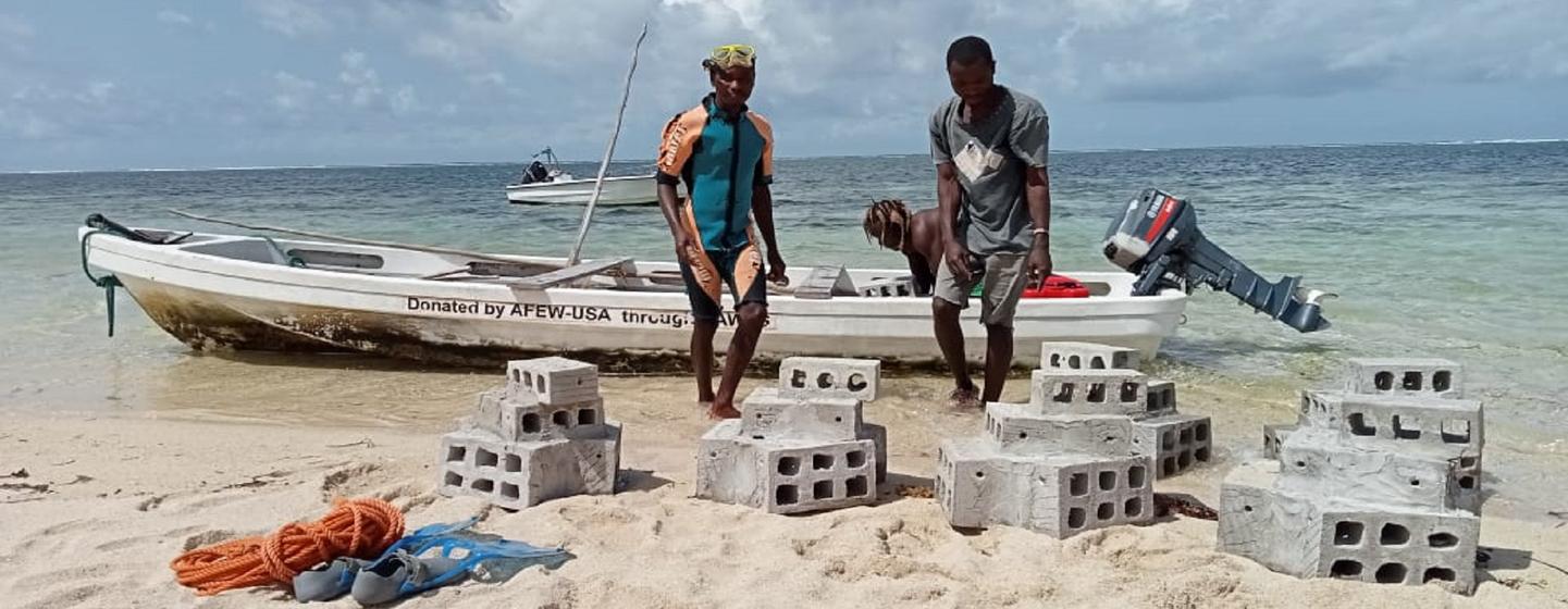 Unos lugareños de Kuruwitu cargan bloques de cemento con corales en una barca, preparados para instalarlos en una zona remota en el mar.