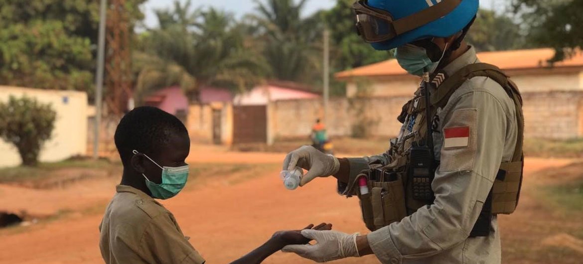 En République centrafricaine, un Casque bleu de la MINUSCA verse du gel hydroalcoolique dans la main d'un enfant.