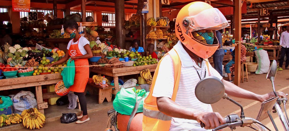 Un conducteur de SafeBoda et un vendeur de marché utilise l'application SafeBoda pour livrer de la nourriture pendant le confinement dû à la Covid-19 à Kampala, en Ouganda.