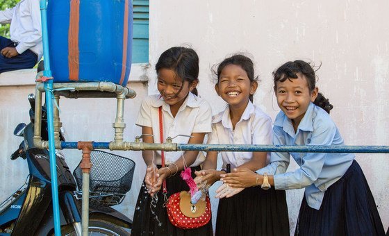 Meninas de uma escola no Camboja lavam as mãos usando a água de uma instalação da escola.