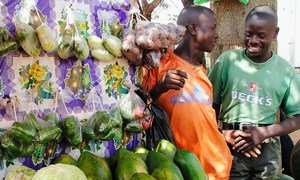 Des marchands ambulants discutent devant leur étal de fruits et legumes sur un marché de Kampala, en Ouganda