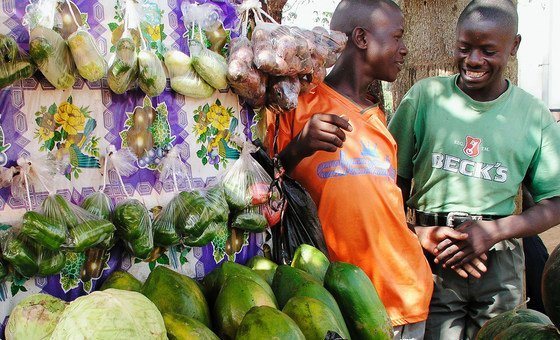 Vendors chatting at a vegetable stand in a marketplace in Kampala, Uganda.