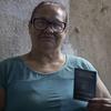 Uma mulher de óculos segura um passaporte.