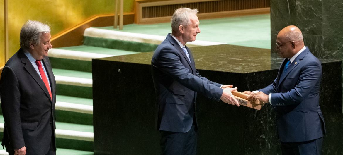 Abdulla Shahid (derecha), Presidente del 76º período de sesiones de la Asamblea General de la ONU, entrega el mazo a Csaba Kőrösi, Presidente del 77º período de sesiones de la Asamblea General de las Naciones Unidas. A la izquierda, el Secretario General 