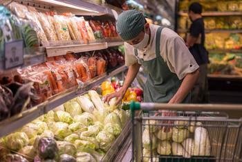 Un empleado coloca verduras en un supermercado en Indonesia