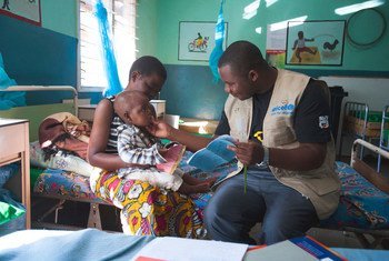 Una madre sostiene a su hijo de 18 meses mientras lo atienden en un hospital del distrito de Balaka en Malawi.