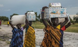 Women carry food assistance received at a WFP emergency distribution point in Thaker, Unity state, South Sudan.